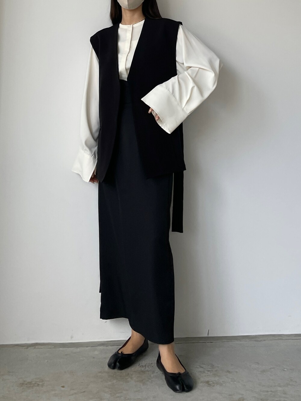 ベージュ系のシャツ/ブラウス、ブラック系のベスト、ブラック系のスカートを着用したレディースの秋コーディネートの4枚目の写真