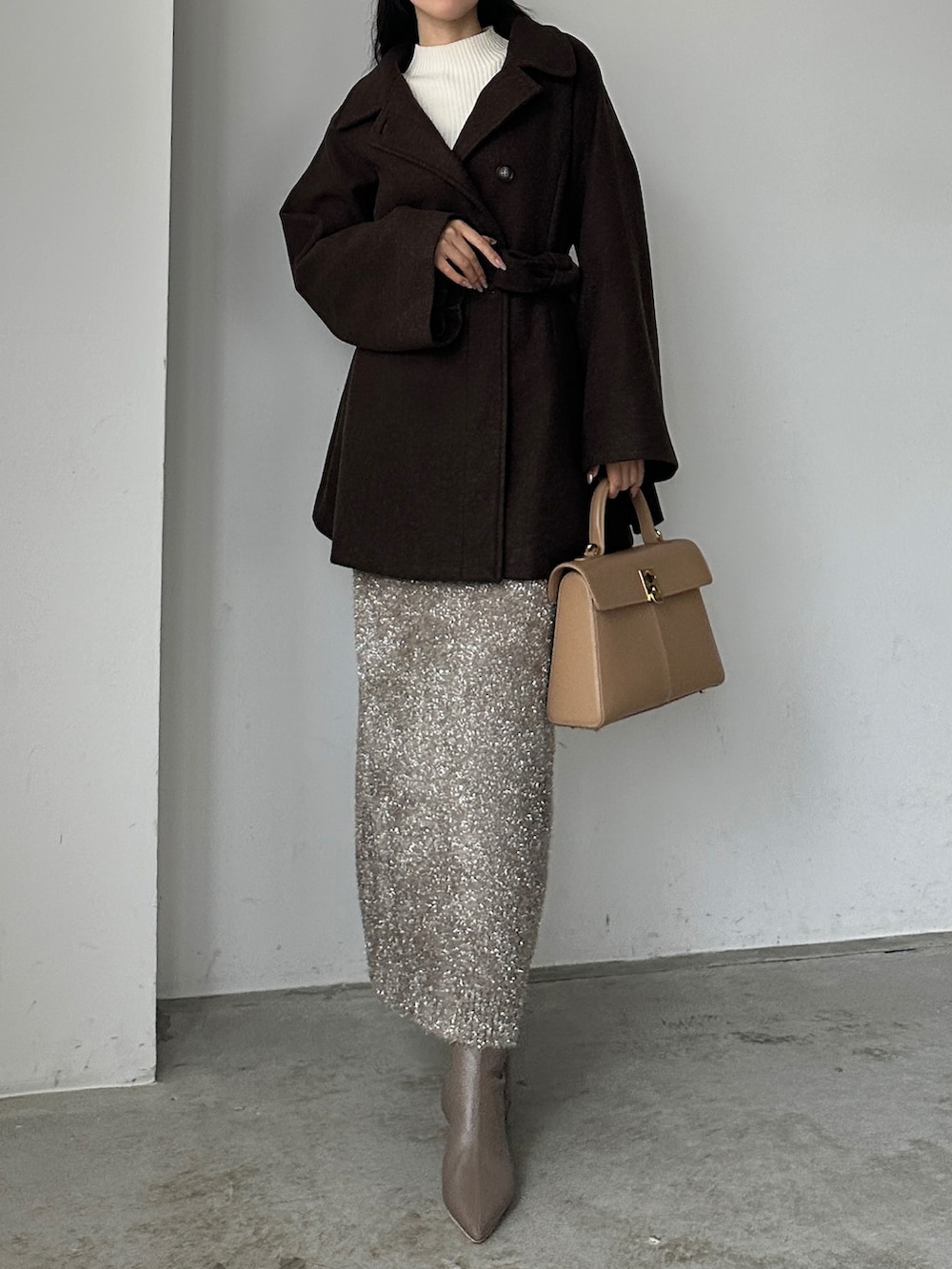 ブラウン系のステンカラーコート、ベージュ系のスカート、ホワイト系のニット/セーターを着用したレディースの秋コーディネートの2枚目の写真