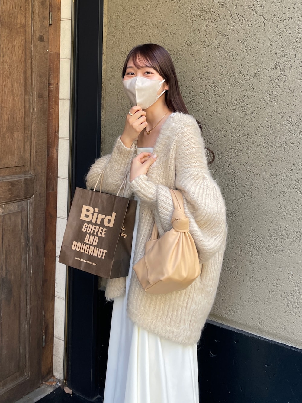 ホワイト系のワンピース、ホワイト系のカーディガン/ボレロ、ベージュ系のバッグを着用したレディースの冬コーディネートの2枚目の写真