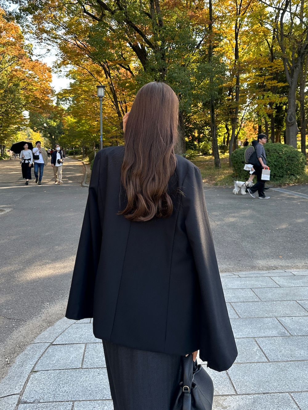 ブラック系のテーラードジャケット、ブラック系のスカート、ホワイト系のニット/セーターを着用したレディースの秋コーディネートの3枚目の写真