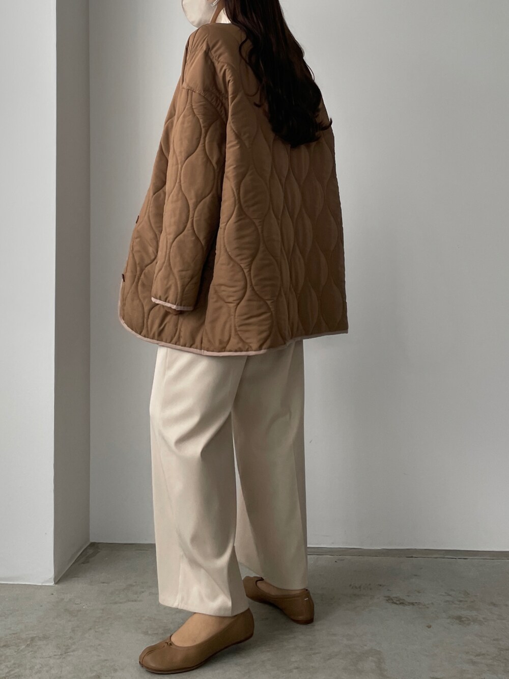 ブラウン系のダウンジャケット/コート、ホワイト系のその他パンツ、ベージュ系のニット/セーターを着用したレディースの秋コーディネートの2枚目の写真