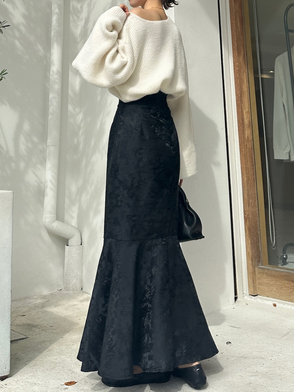 ホワイト系のニット/セーター、ブラック系のスカート、ブラック系のシューズを着用したレディースの秋コーディネートの4枚目の写真