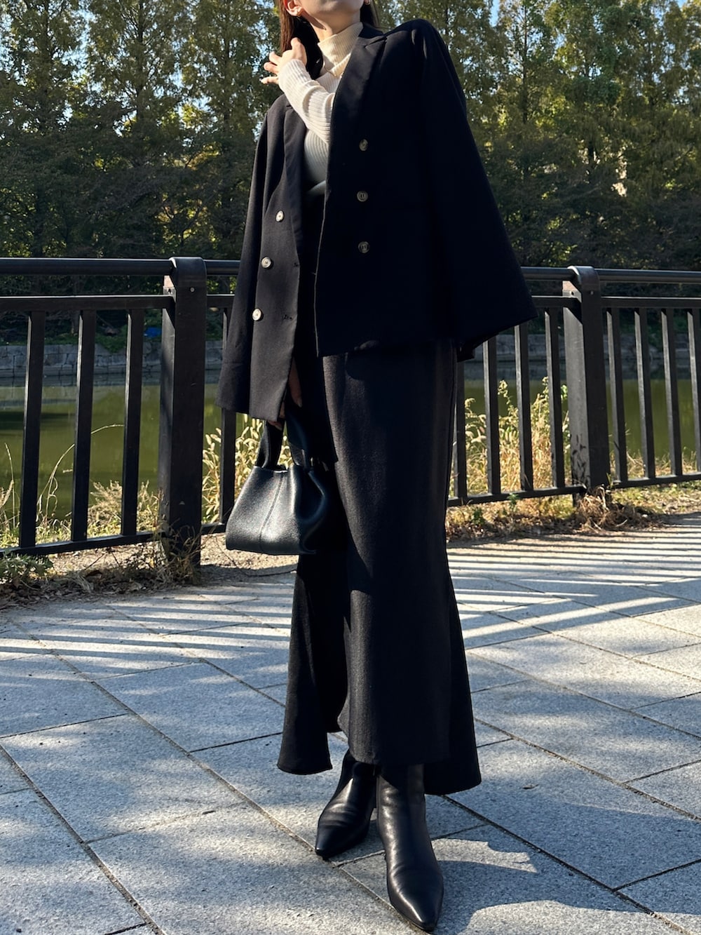 ブラック系のテーラードジャケット、ブラック系のスカート、ホワイト系のニット/セーターを着用したレディースの秋コーディネートの5枚目の写真