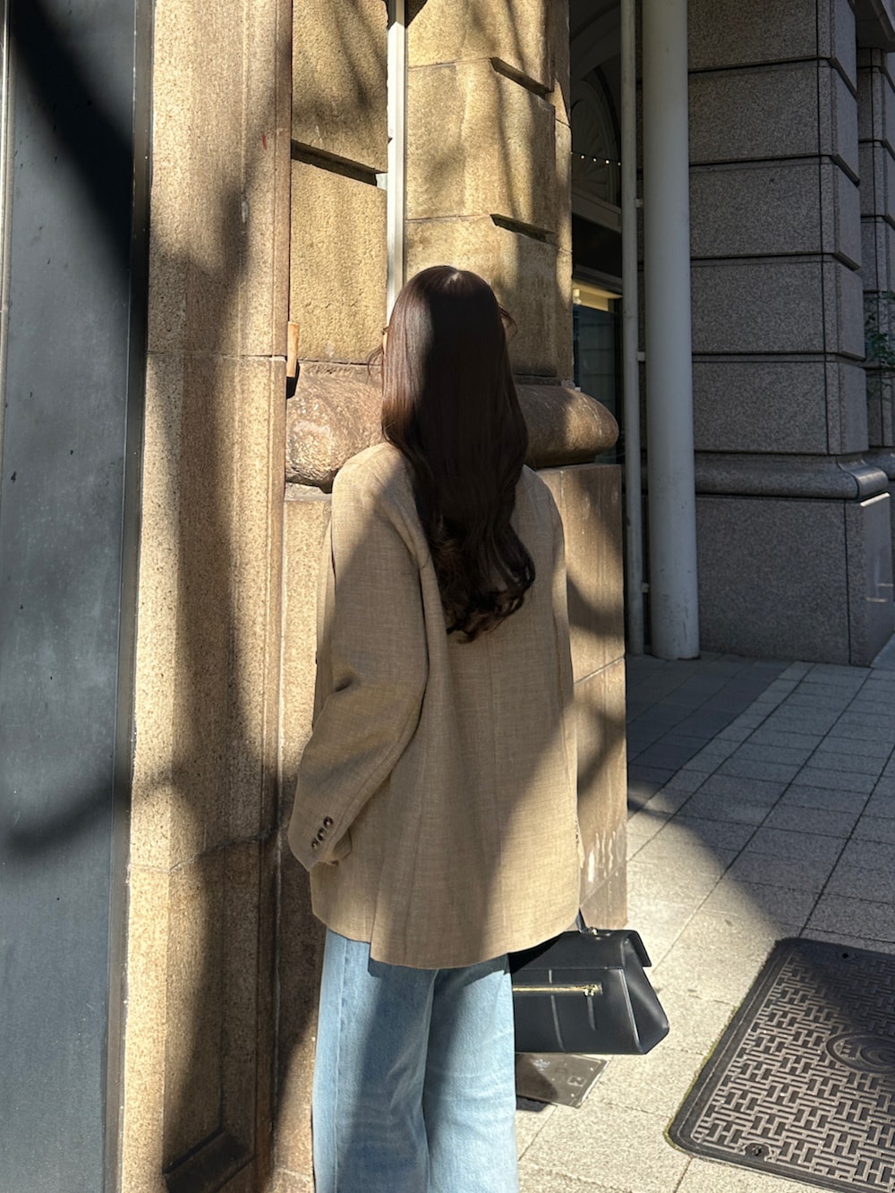 ブラック系のハンドバッグ、ブルー系のパンツを着用したレディースの冬コーディネートの3枚目の写真