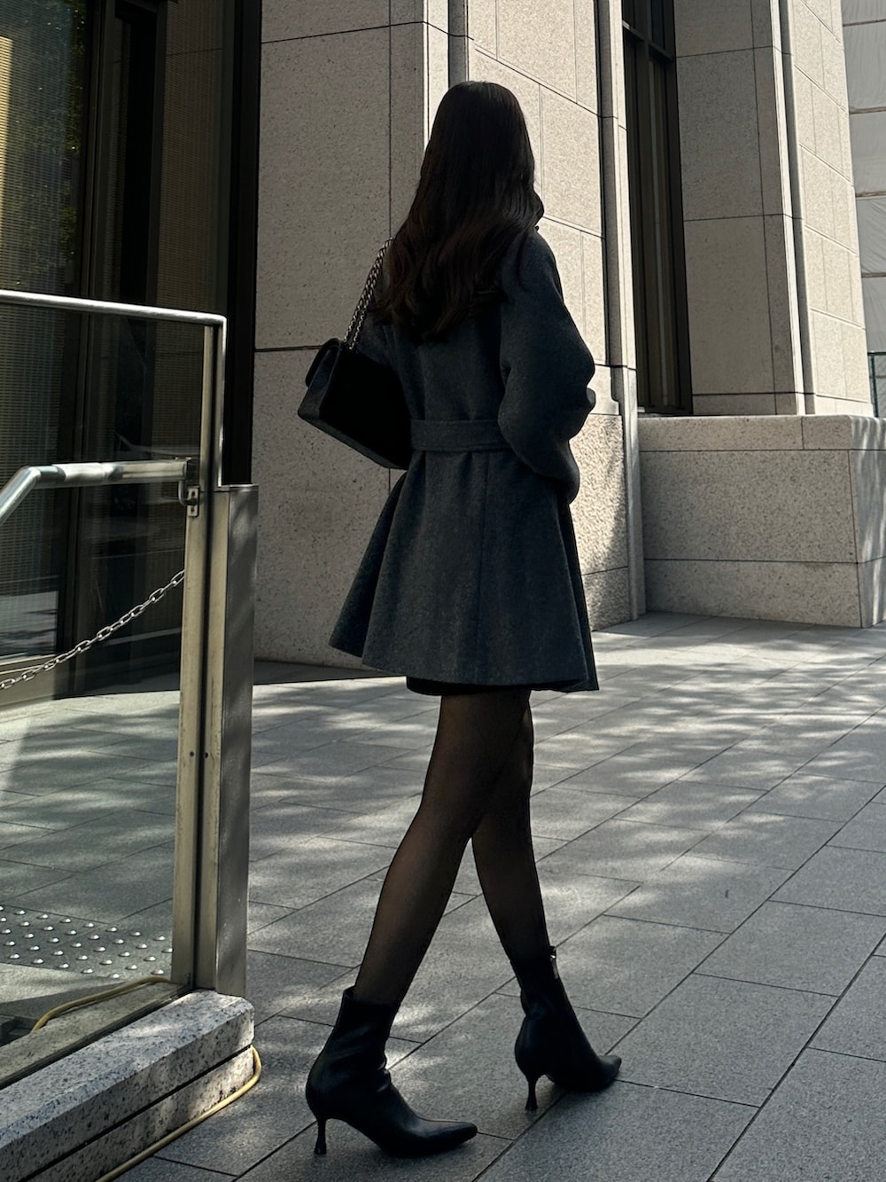 グレー系のステンカラーコートを着用したレディースの秋コーディネートの3枚目の写真