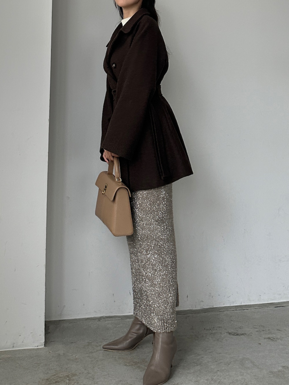 ブラウン系のステンカラーコート、ベージュ系のスカート、ホワイト系のニット/セーターを着用したレディースの秋コーディネートの3枚目の写真