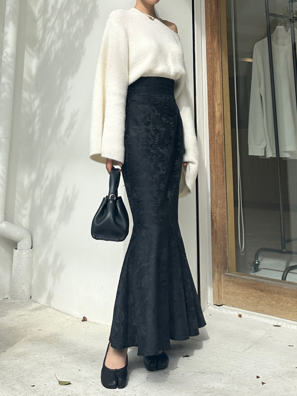 ホワイト系のニット/セーター、ブラック系のスカート、ブラック系のシューズを着用したレディースの秋コーディネートの2枚目の写真