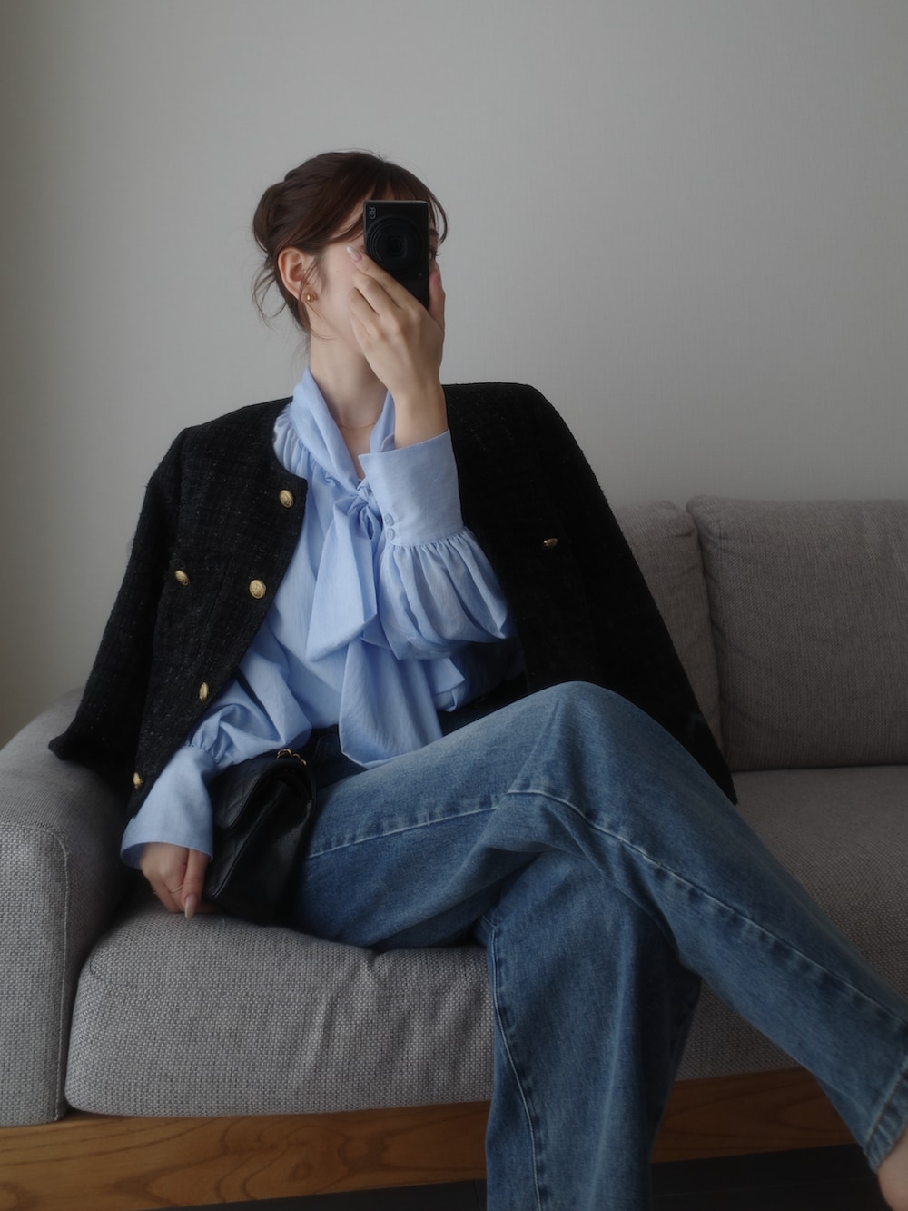 ブラック系のノーカラージャケット、ブルー系のデニムパンツを着用したレディースの春コーディネートの3枚目の写真