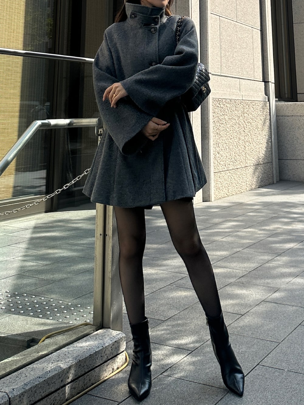 グレー系のステンカラーコートを着用したレディースの秋コーディネートの2枚目の写真