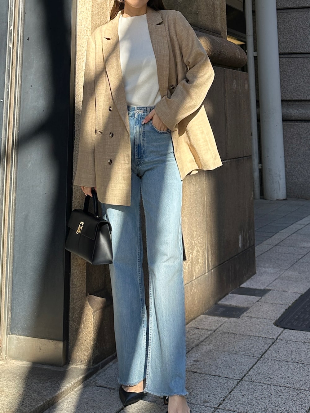 ブラック系のハンドバッグ、ブルー系のパンツを着用したレディースの冬コーディネートの2枚目の写真