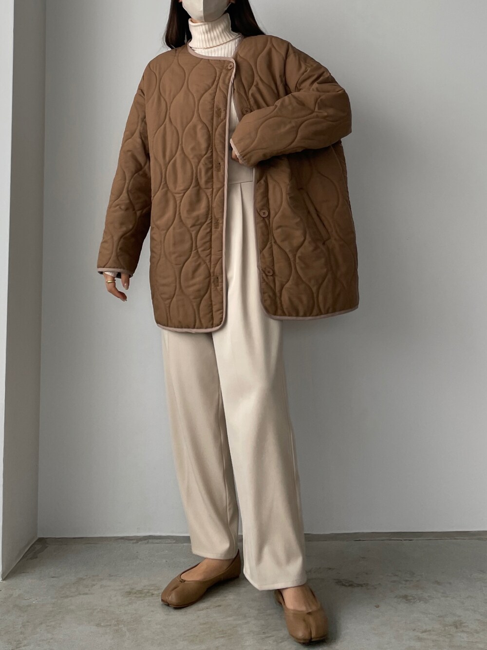 ブラウン系のダウンジャケット/コート、ホワイト系のその他パンツ、ベージュ系のニット/セーターを着用したレディースの秋コーディネートの3枚目の写真