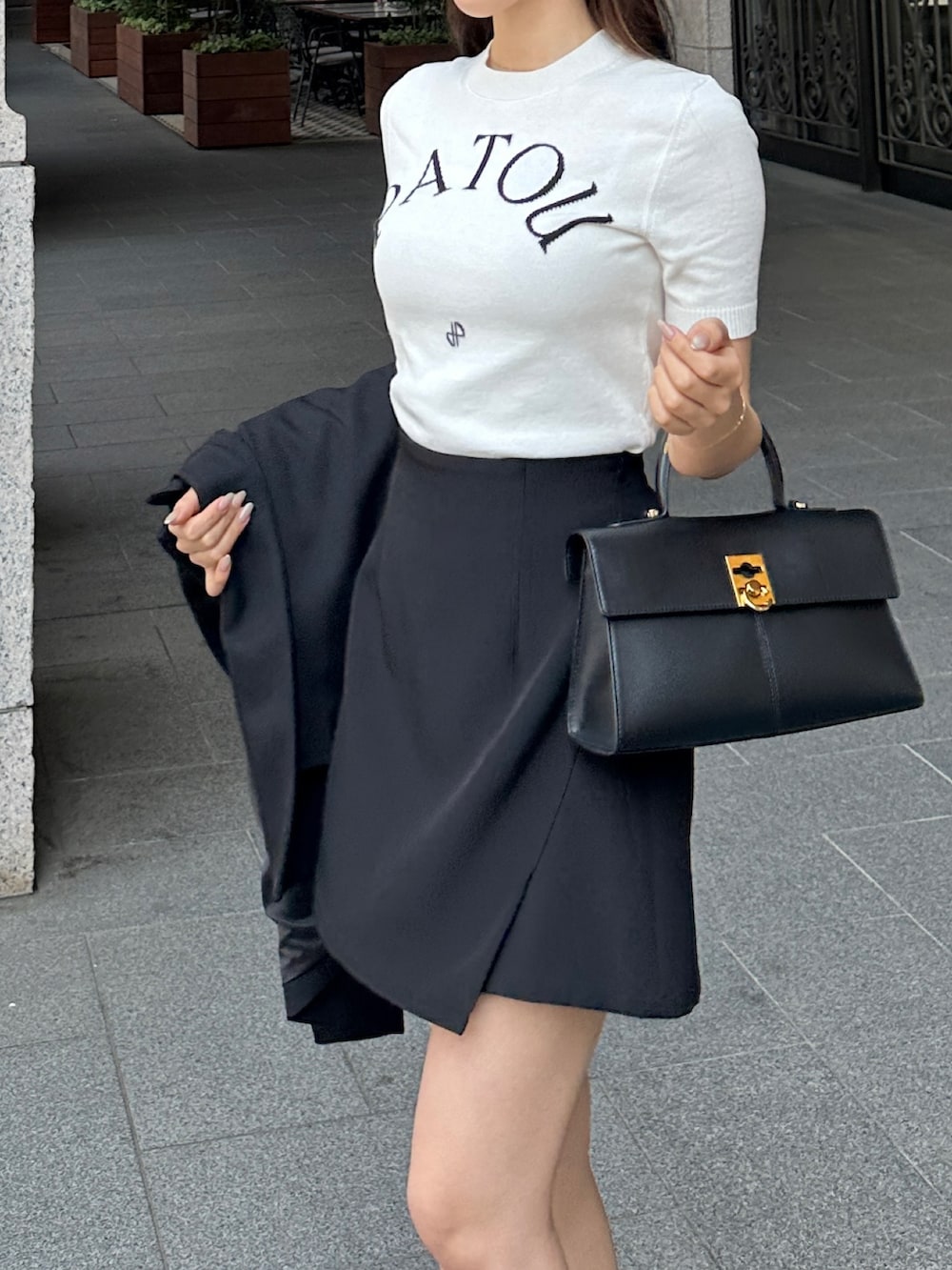 ブラック系のハンドバッグ、ブラック系のスカート、ブラック系のテーラードジャケットを着用したレディースの春コーディネートの4枚目の写真