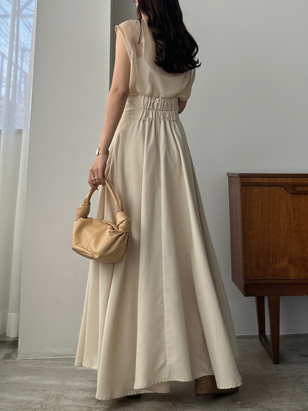 ベージュ系のスカート、ホワイト系のシャツ/ブラウス、ベージュ系のバッグを着用したレディースの春コーディネートの2枚目の写真