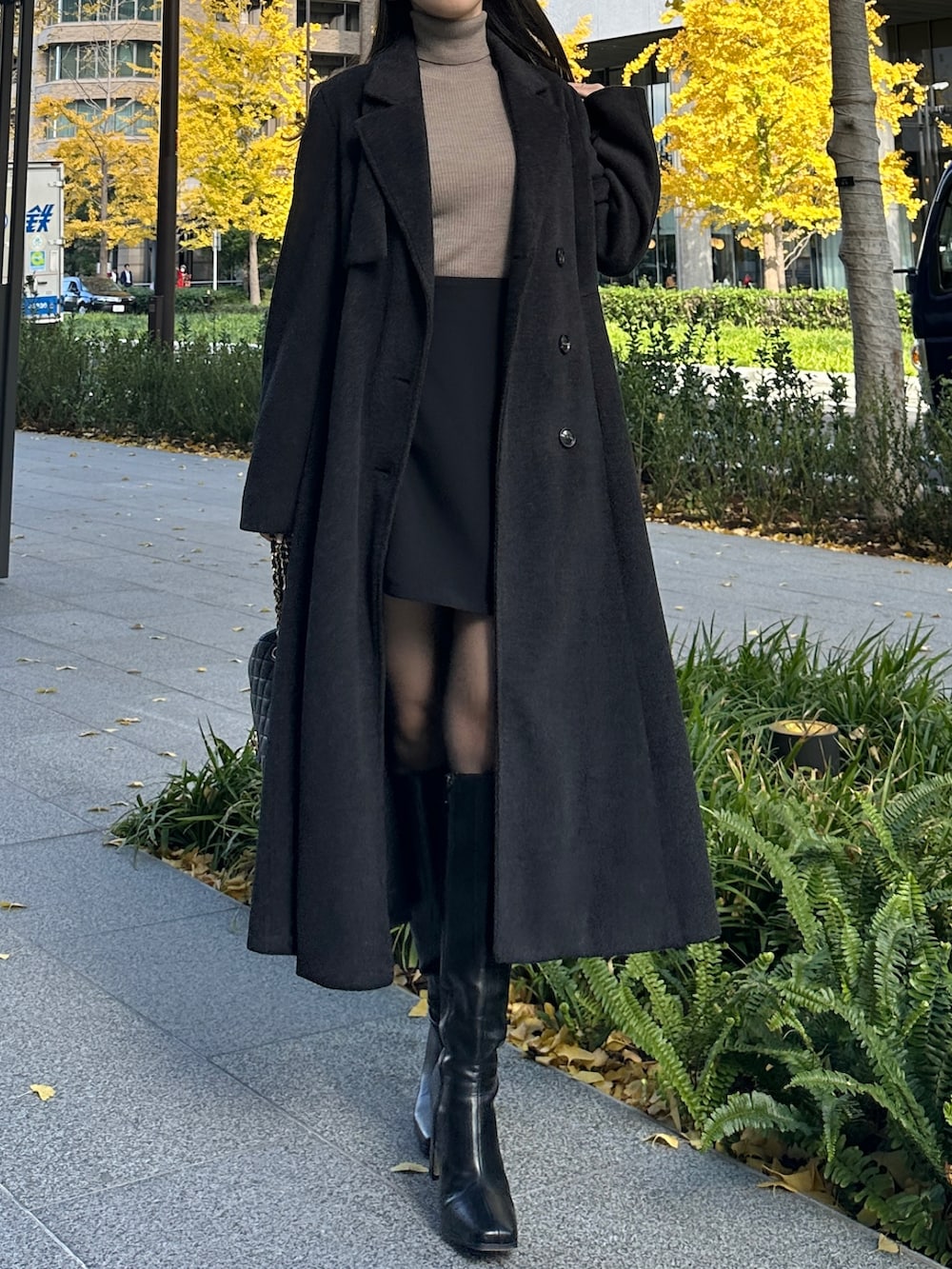 ブラック系のチェスターコート、ブラック系のスカートを着用したレディースの冬コーディネートの4枚目の写真