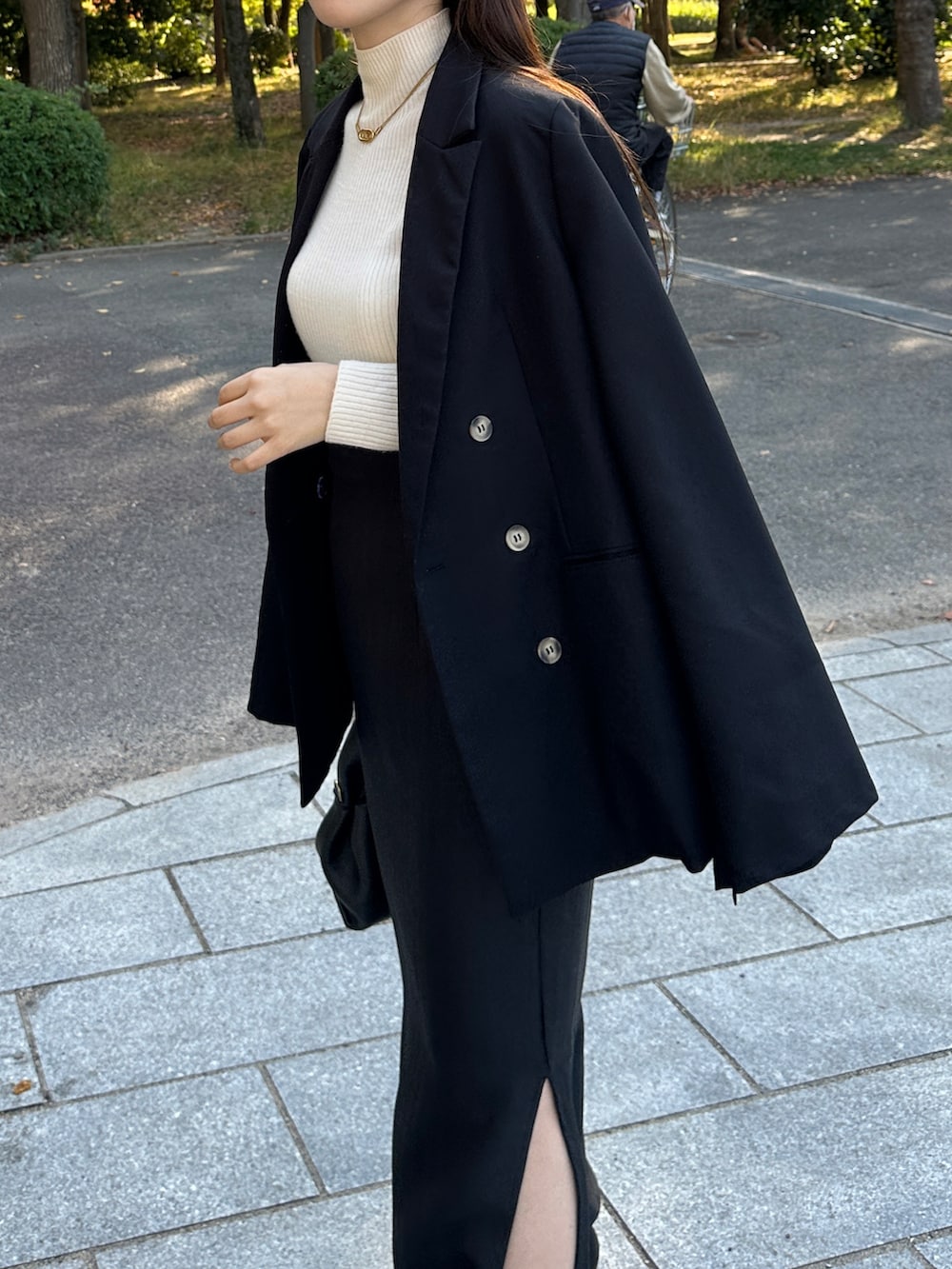 ブラック系のテーラードジャケット、ブラック系のスカート、ホワイト系のニット/セーターを着用したレディースの秋コーディネートの2枚目の写真