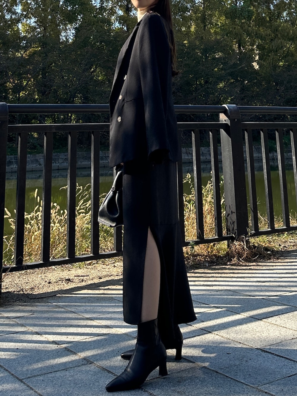 ブラック系のテーラードジャケット、ブラック系のスカート、ホワイト系のニット/セーターを着用したレディースの秋コーディネートの4枚目の写真