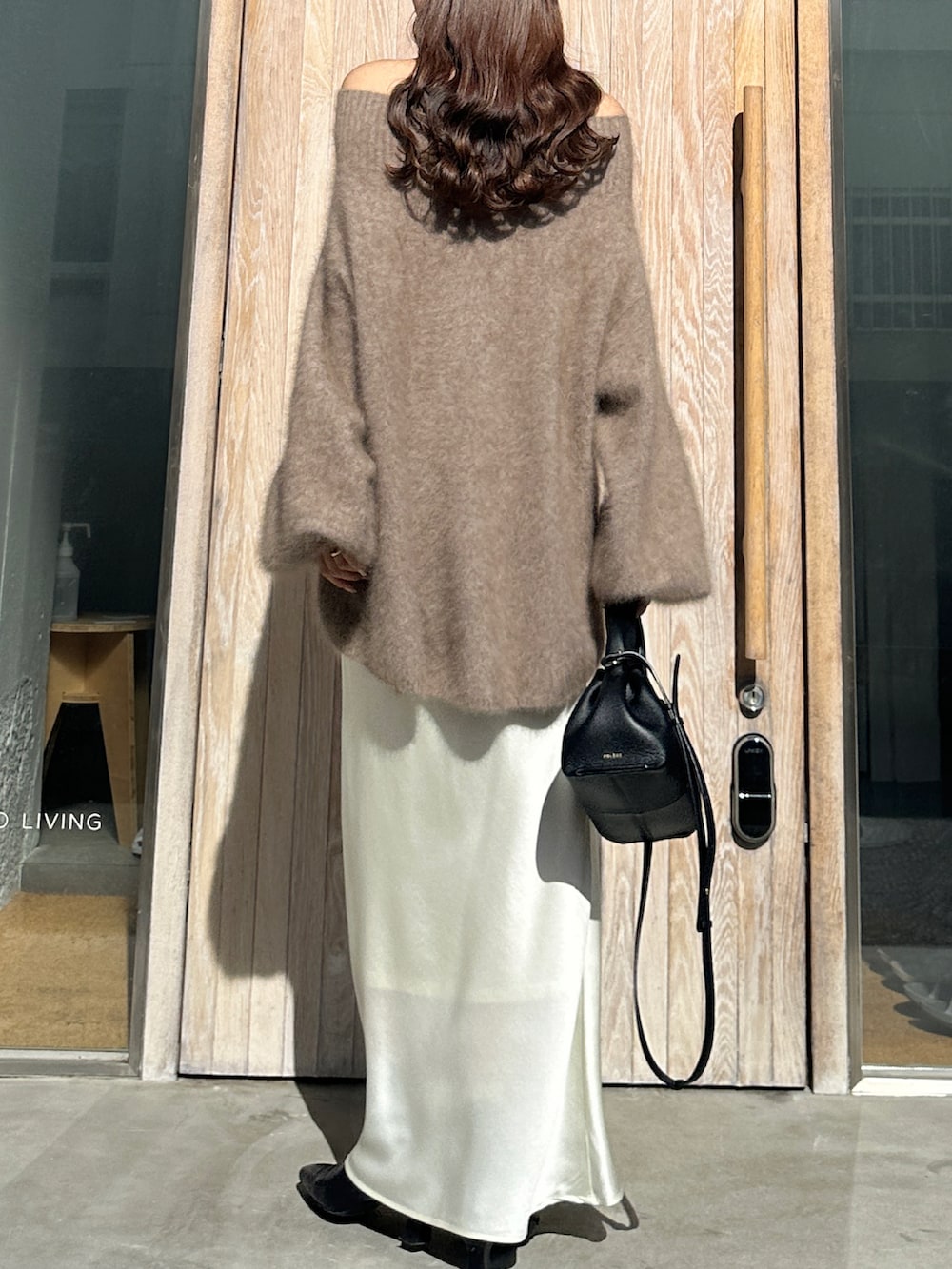 ブラウン系のニット/セーター、ホワイト系のスカート、ブラック系のブーツを着用したレディースの冬コーディネートの2枚目の写真