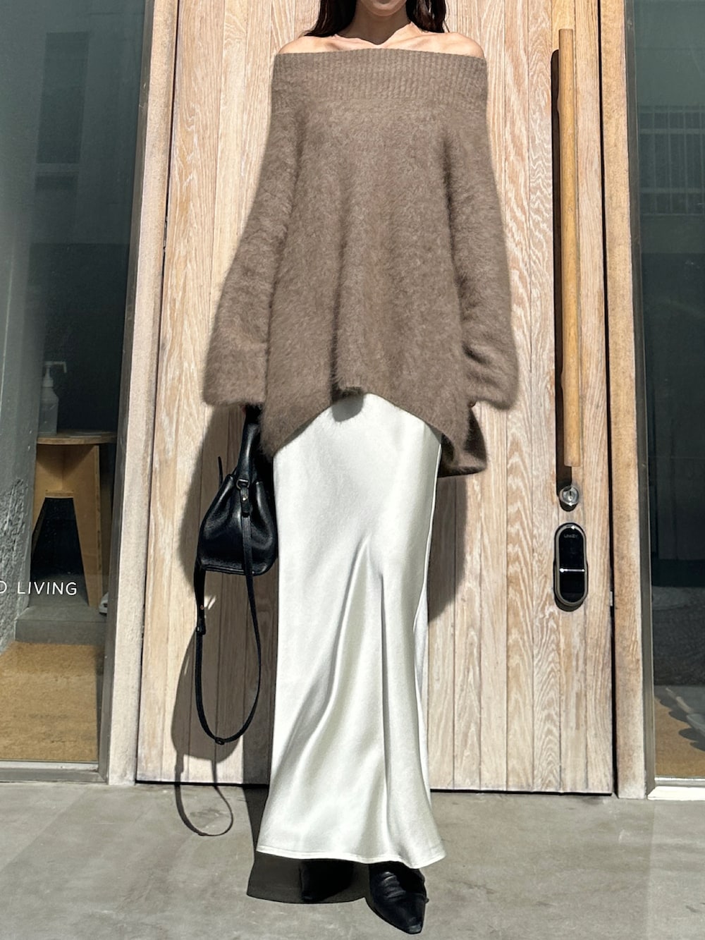 ブラウン系のニット/セーター、ホワイト系のスカート、ブラック系のブーツを着用したレディースの冬コーディネートの3枚目の写真