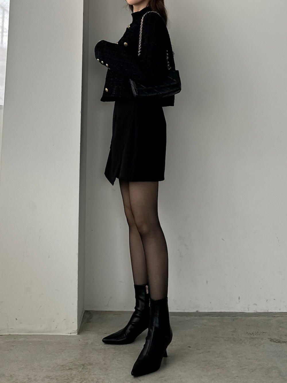 ブラック系のブーツ、ブラック系のスカート、ブラック系のノーカラージャケットを着用したレディースの秋コーディネートの3枚目の写真