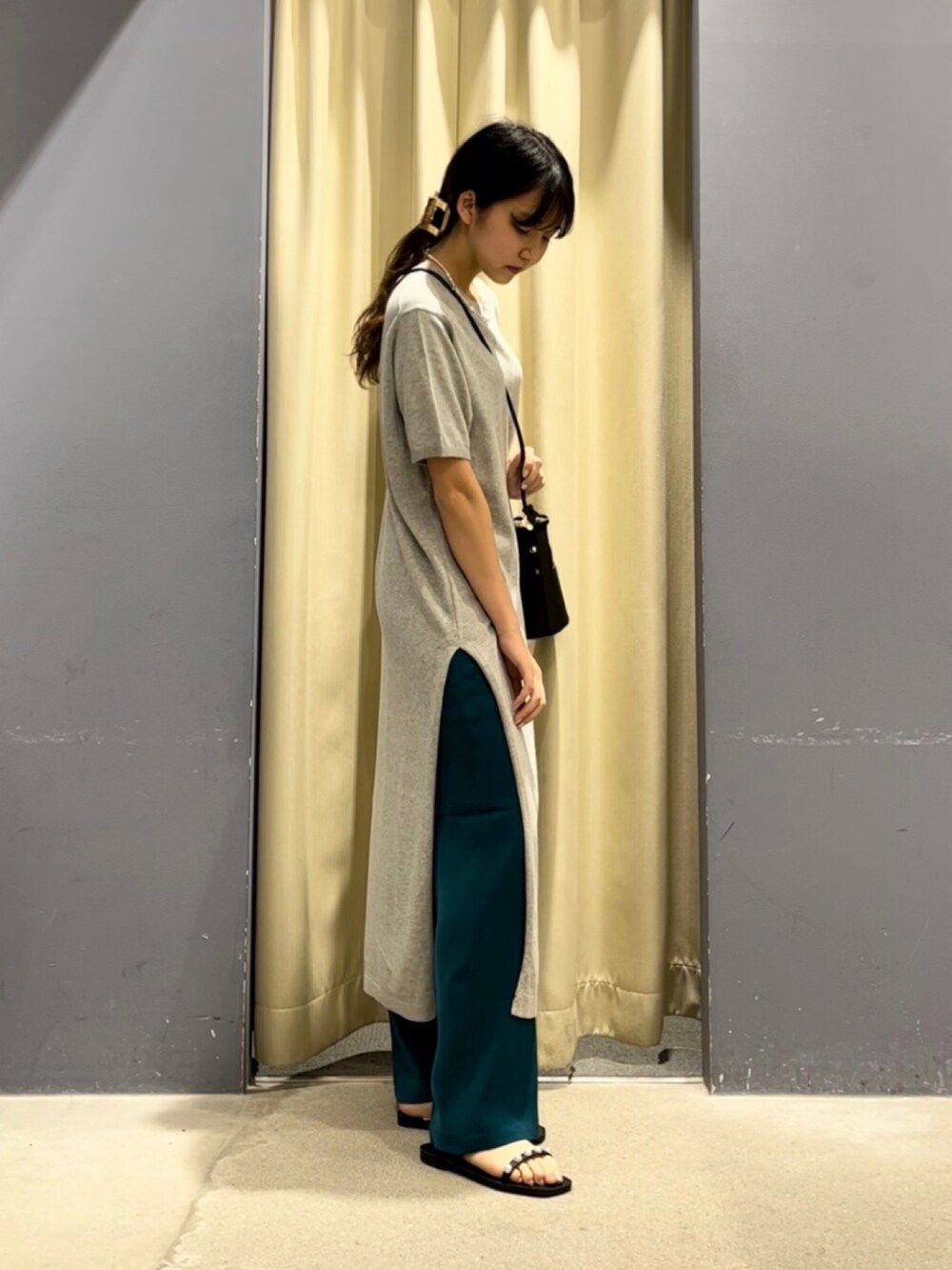 グレー系のワンピース、ブラック系のショルダーバッグ、グリーン系のスラックスを着用したレディースの春コーディネートの2枚目の写真