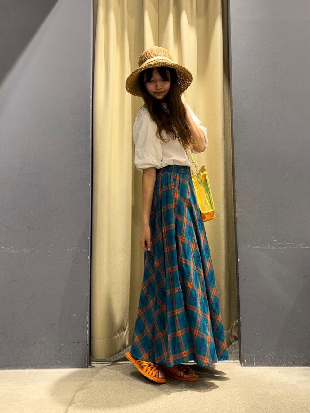 イエロー系のショルダーバッグ、ホワイト系のTシャツ/カットソー、グリーン系のスカートを着用したレディースの夏コーディネートの2枚目の写真