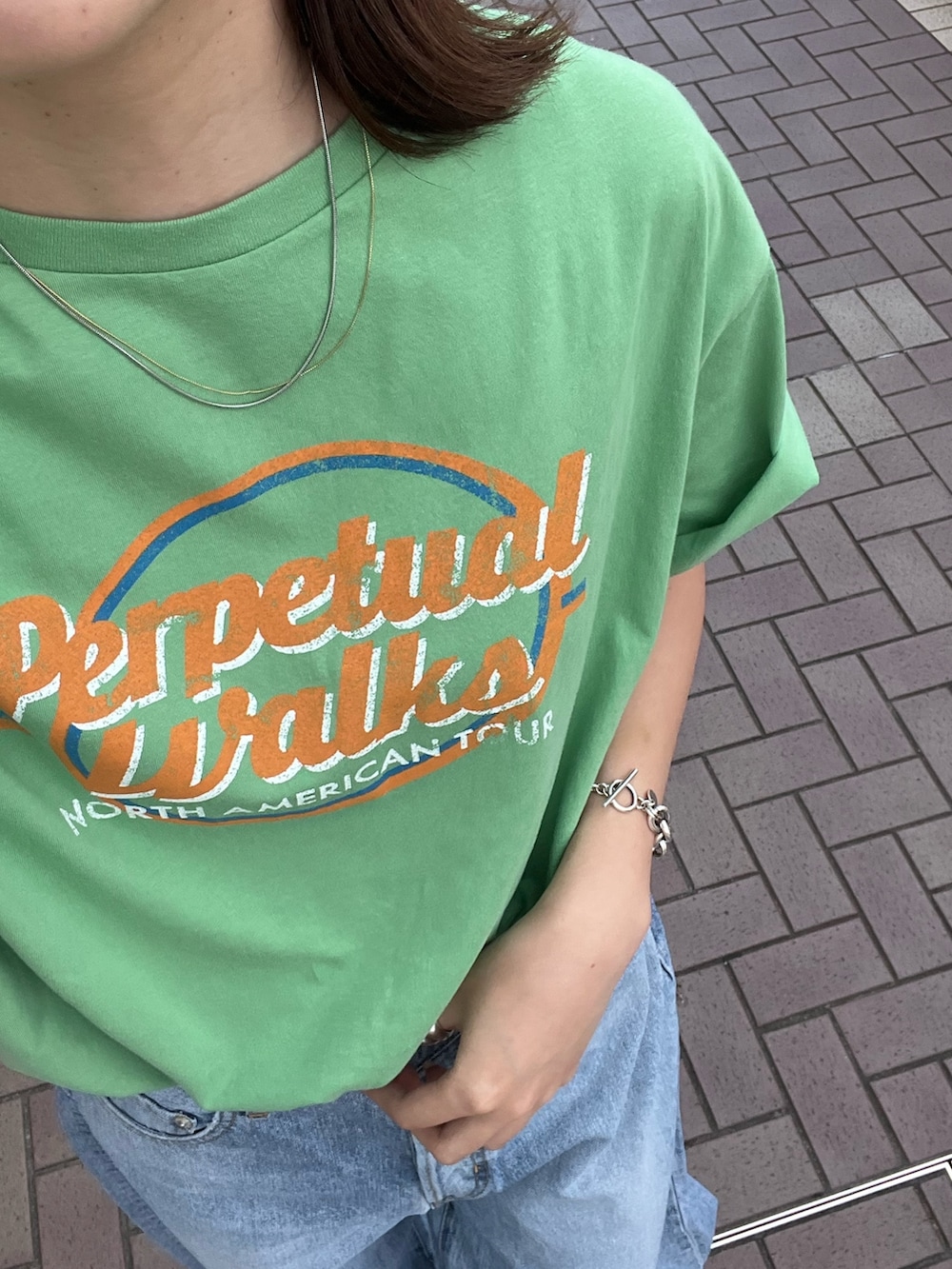 ブラック系のサンダル、グリーン系のTシャツ/カットソー、ブルー系のデニムパンツを着用したレディースの夏コーディネートの5枚目の写真