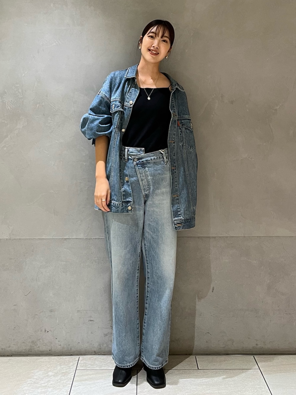 ブルー系のデニムジャケット、ブルー系のデニムパンツ、ブラック系のキャミソールを着用したレディースの秋コーディネートの2枚目の写真