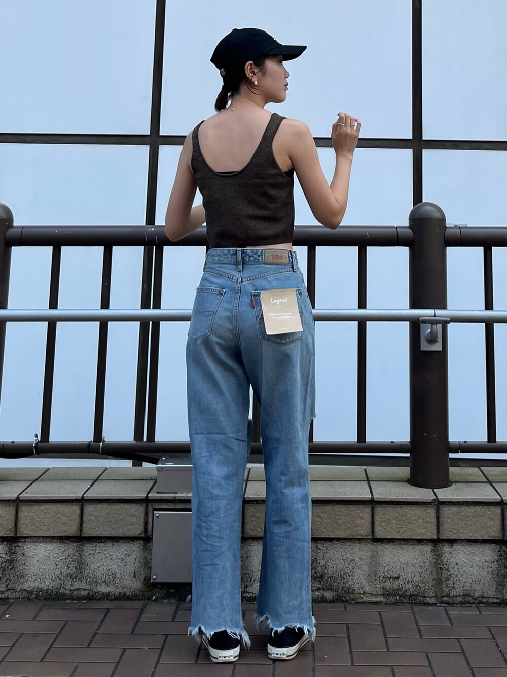 ブラウン系のベスト、ブルー系のデニムパンツ、ブラック系のキャップを着用したレディースの夏コーディネートの5枚目の写真