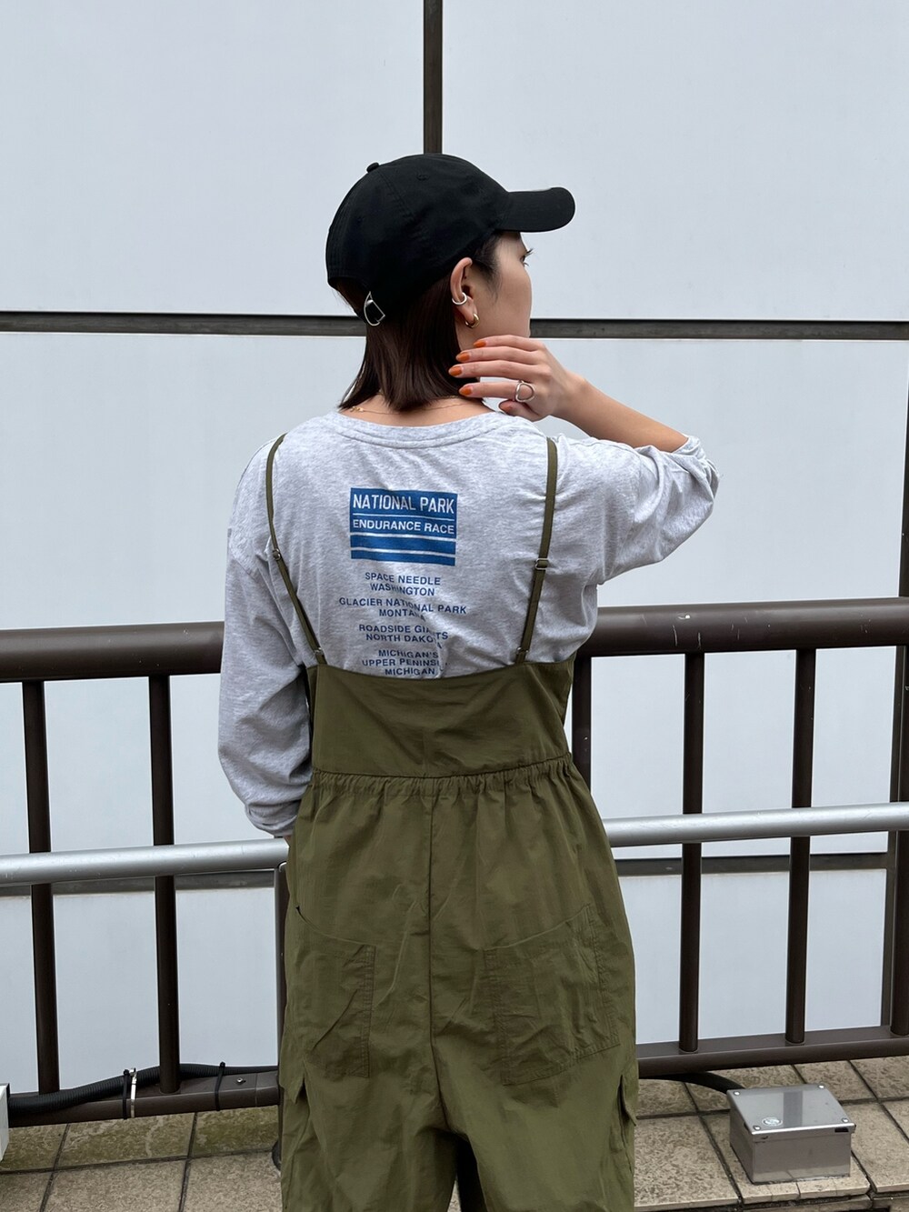 グリーン系のサロペット/オーバーオール、グレー系のTシャツ/カットソー、ベージュ系のステンカラーコートを着用したレディースの冬コーディネートの6枚目の写真