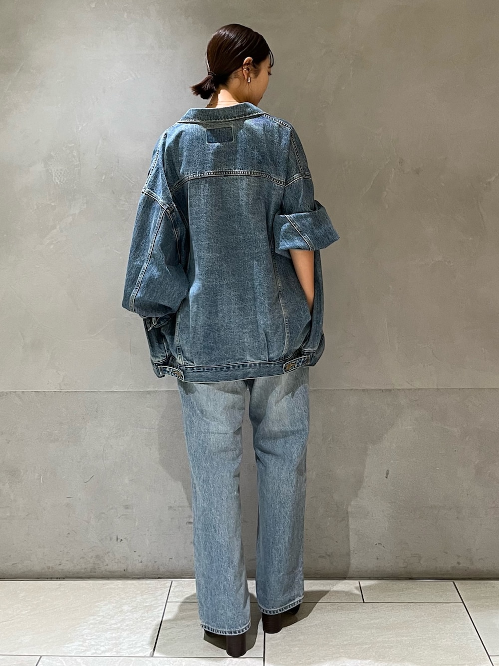 ブルー系のデニムジャケット、ブルー系のデニムパンツ、ブラック系のキャミソールを着用したレディースの秋コーディネートの4枚目の写真