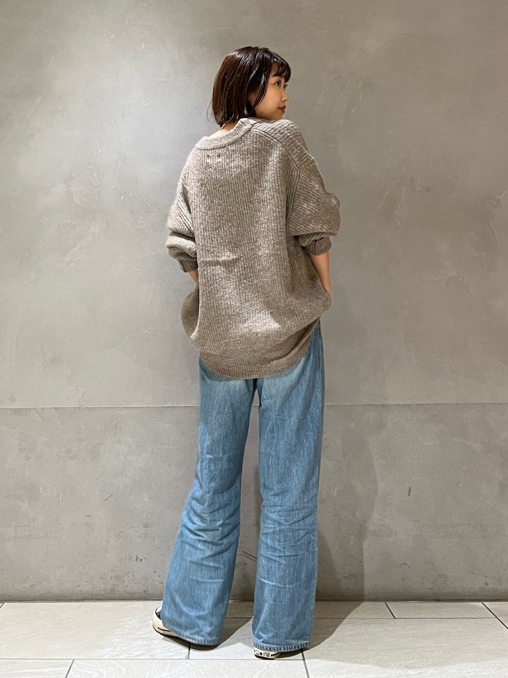 グレー系のカーディガン/ボレロ、ブラック系のキャミソール、ブルー系のデニムパンツを着用したレディースの秋コーディネートの4枚目の写真