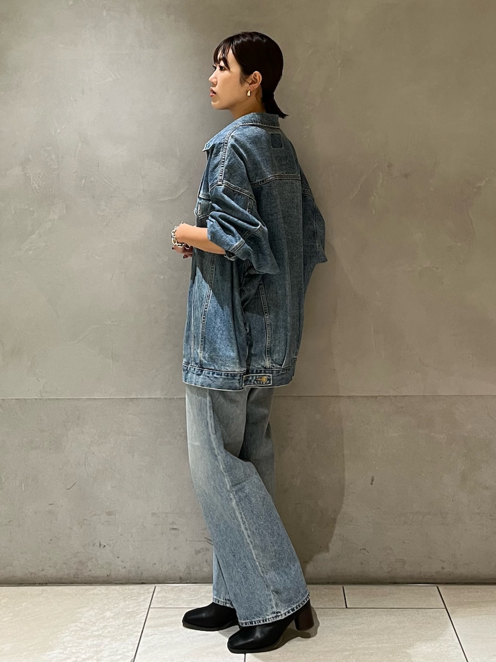 ブルー系のデニムジャケット、ブルー系のデニムパンツ、ブラック系のキャミソールを着用したレディースの秋コーディネートの3枚目の写真