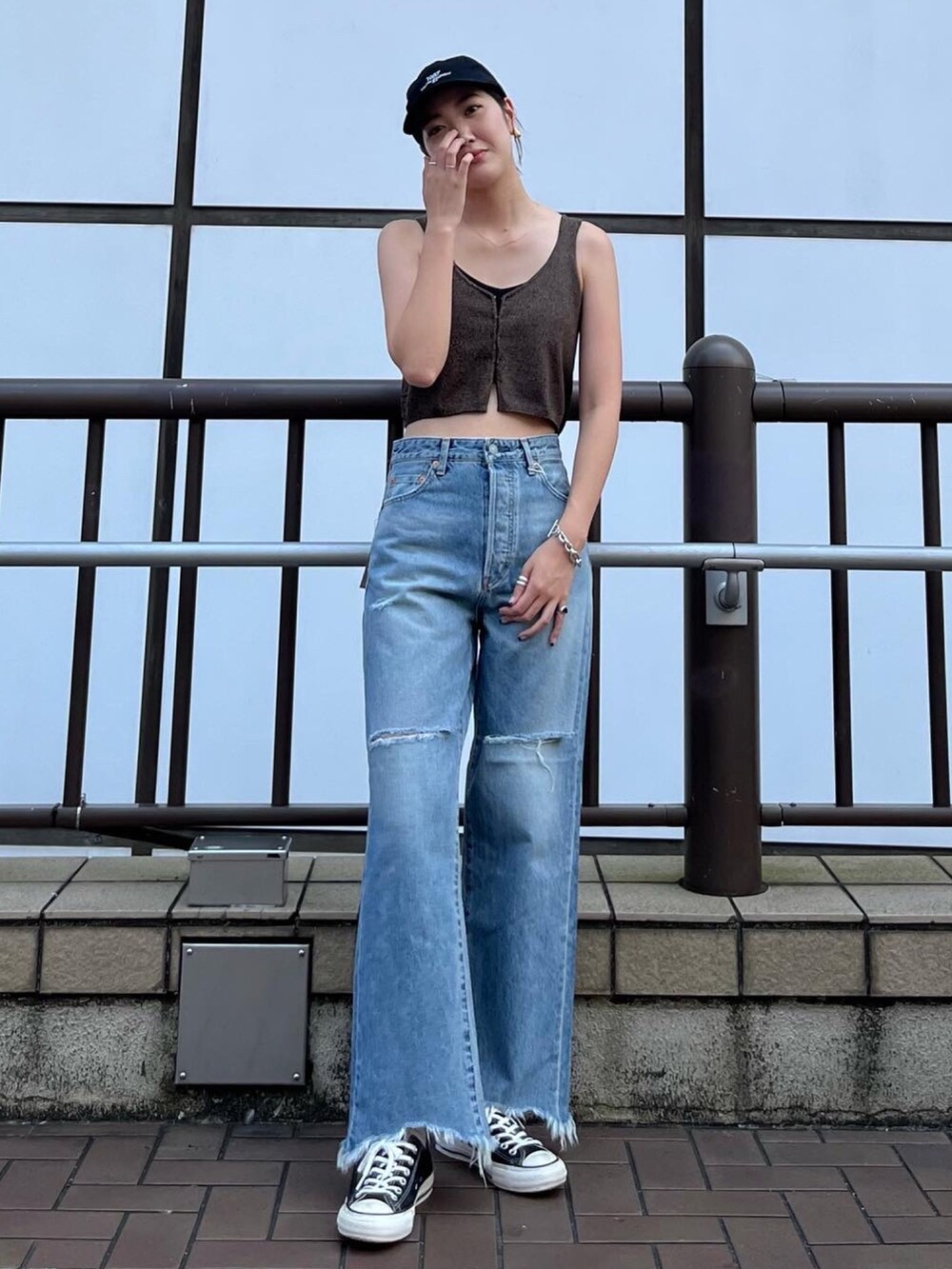 ブラウン系のベスト、ブルー系のデニムパンツ、ブラック系のキャップを着用したレディースの夏コーディネートの2枚目の写真