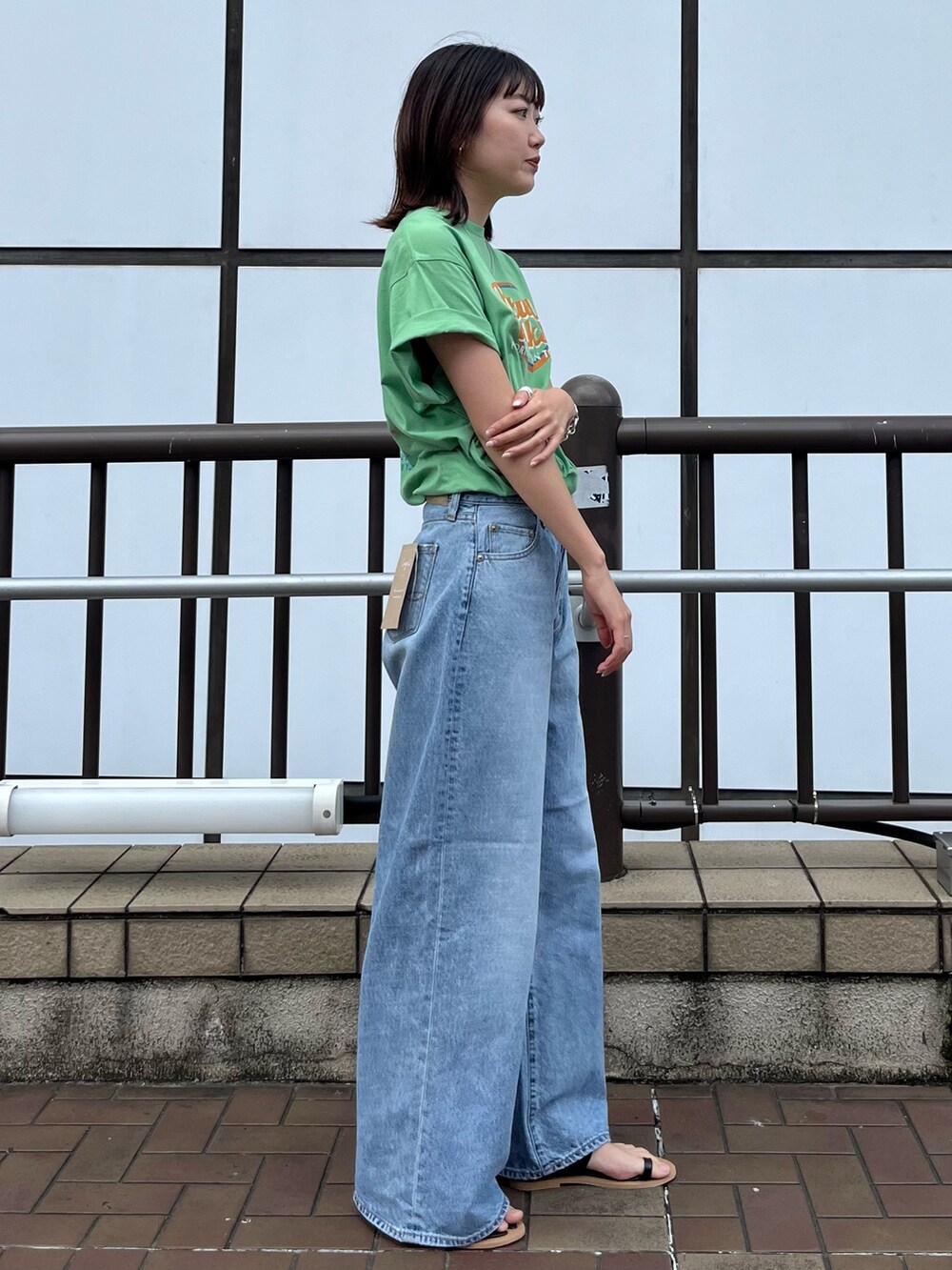 ブラック系のサンダル、グリーン系のTシャツ/カットソー、ブルー系のデニムパンツを着用したレディースの夏コーディネートの3枚目の写真