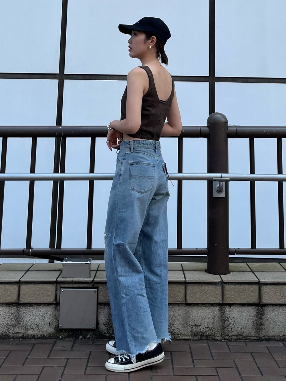 ブラウン系のベスト、ブルー系のデニムパンツ、ブラック系のキャップを着用したレディースの夏コーディネートの4枚目の写真
