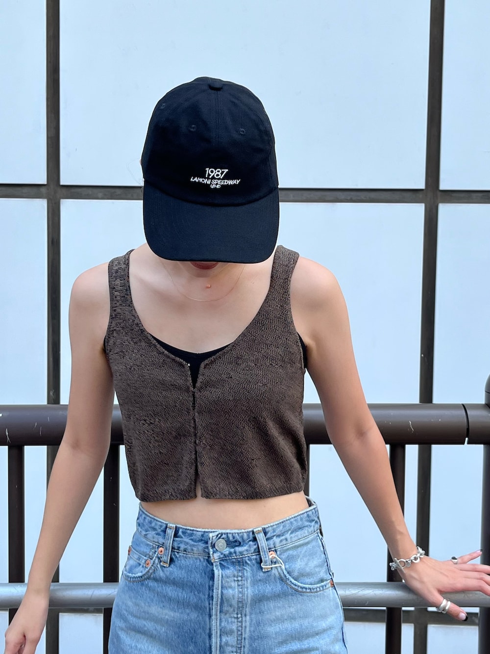 ブラウン系のベスト、ブルー系のデニムパンツ、ブラック系のキャップを着用したレディースの夏コーディネートの6枚目の写真