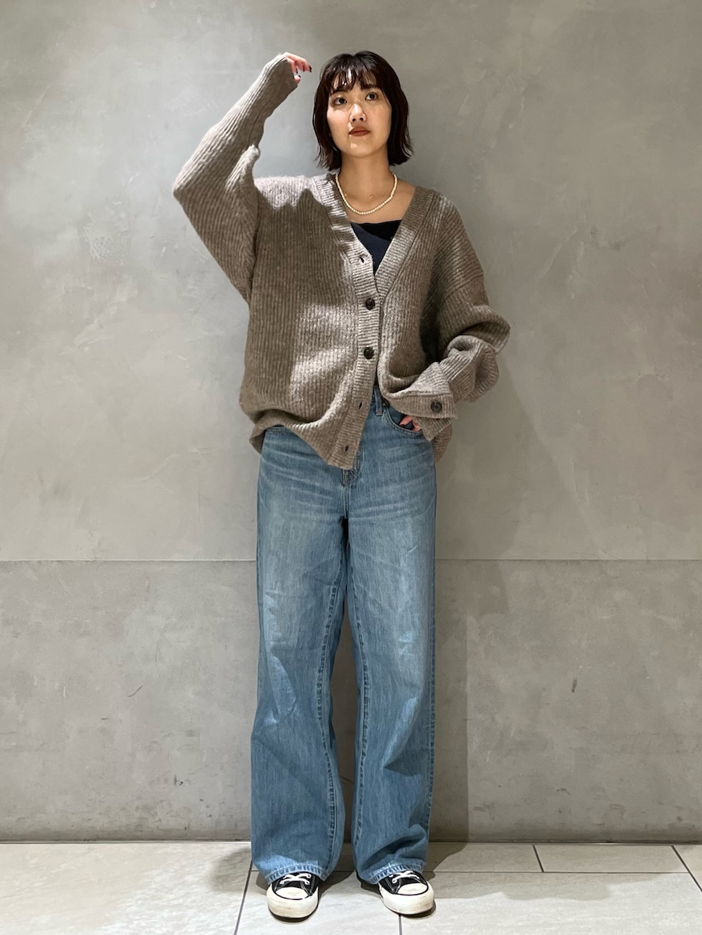 グレー系のカーディガン/ボレロ、ブラック系のキャミソール、ブルー系のデニムパンツを着用したレディースの秋コーディネートの2枚目の写真