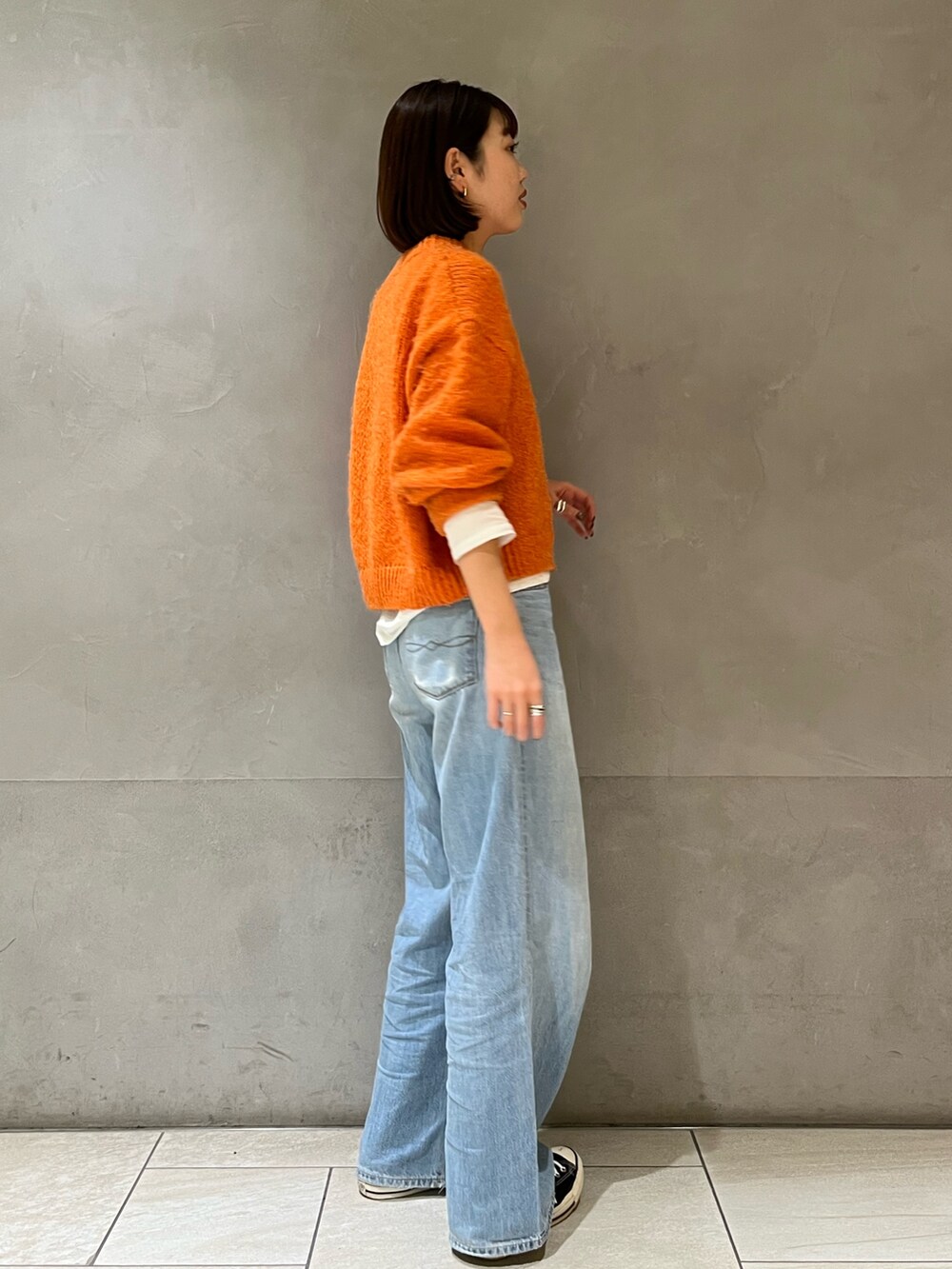 オレンジ系のニット/セーター、ブルー系のデニムパンツを着用したレディースの冬コーディネートの3枚目の写真