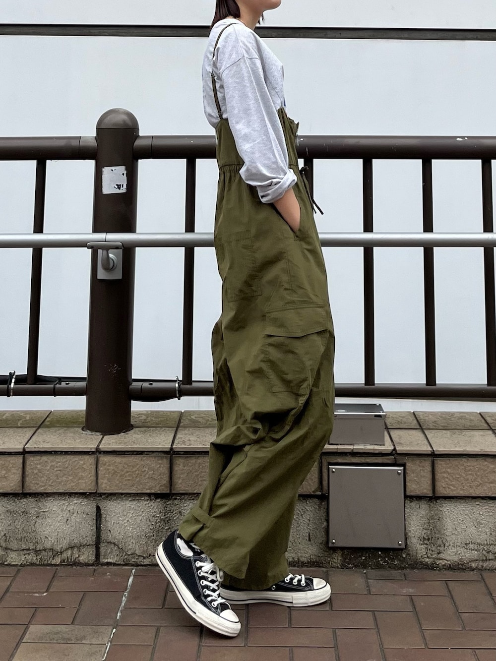グリーン系のサロペット/オーバーオール、グレー系のTシャツ/カットソー、ベージュ系のステンカラーコートを着用したレディースの冬コーディネートの4枚目の写真
