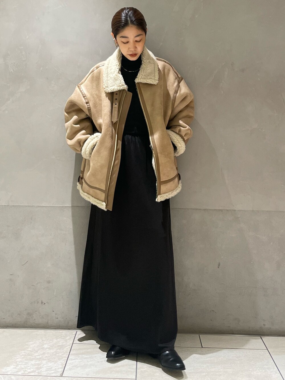 ベージュ系のムートンコート、ブラック系のTシャツ/カットソー、ブラック系のスカートを着用したレディースの秋コーディネートの2枚目の写真