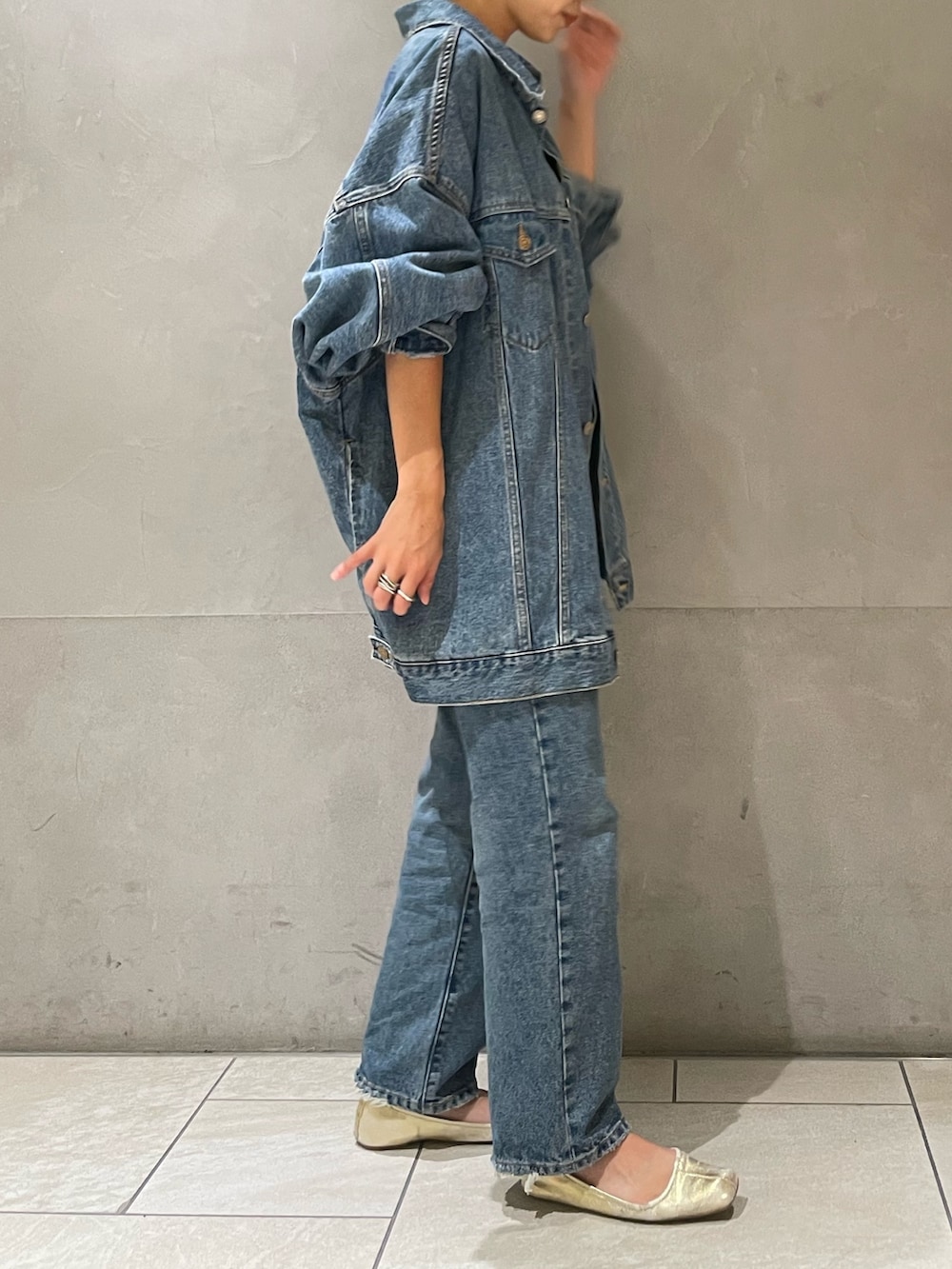 ブルー系のデニムジャケット、ブルー系のデニムパンツ、ブラック系のキャミソールを着用したレディースの秋コーディネートの4枚目の写真