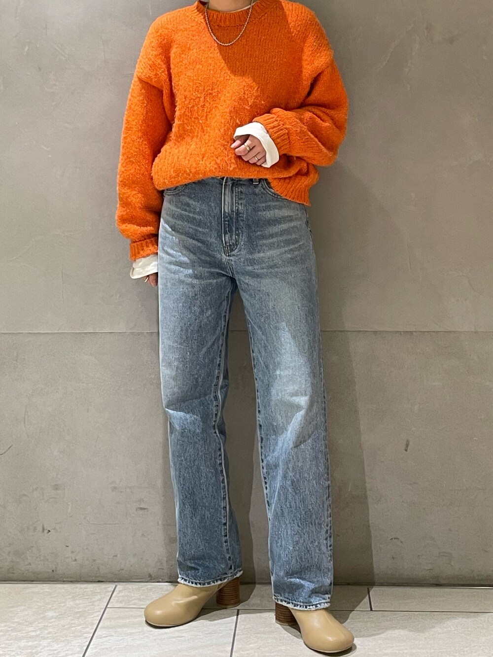 オレンジ系のニット/セーター、ホワイト系のTシャツ/カットソーを着用したレディースの冬コーディネートの2枚目の写真