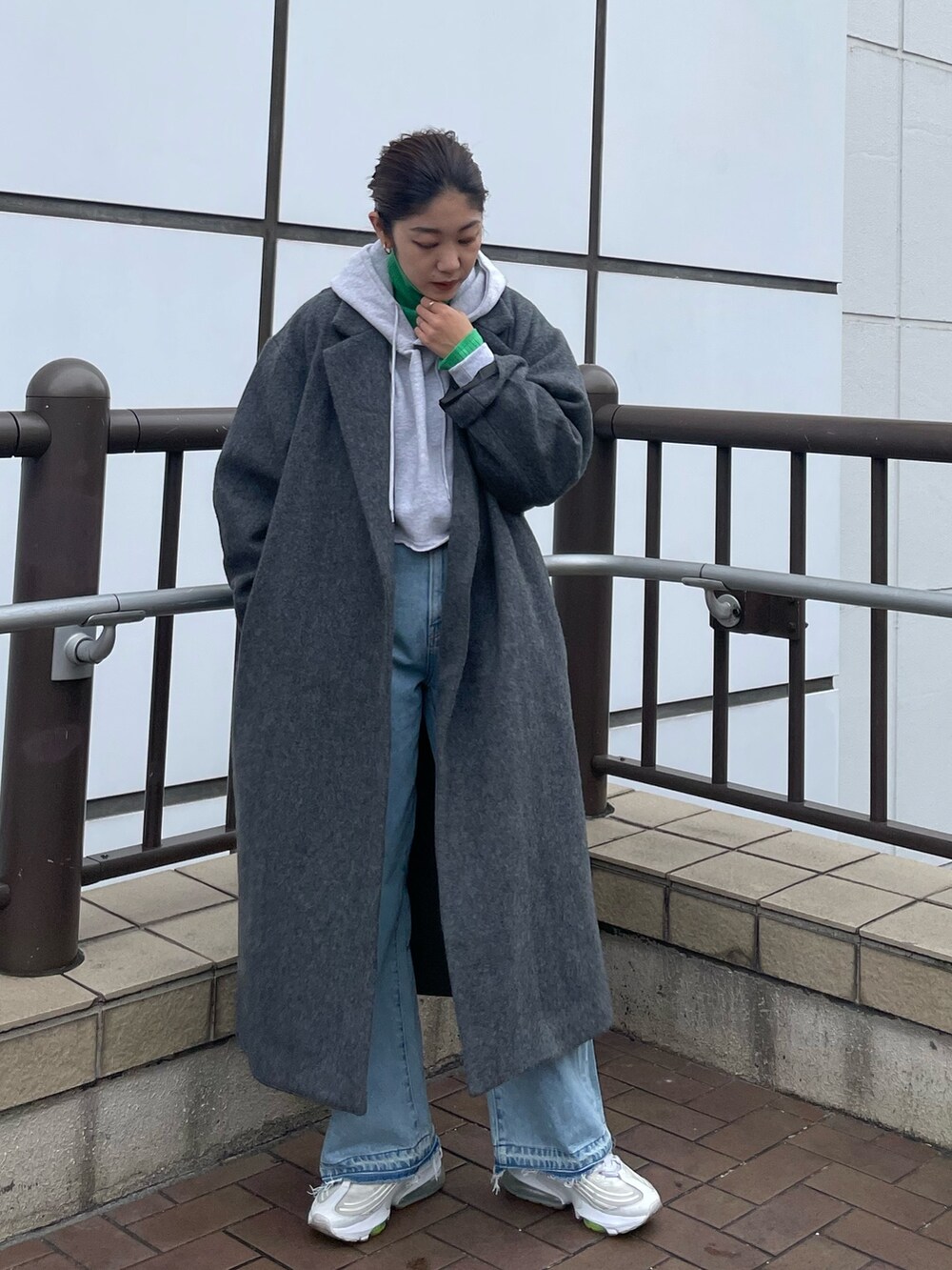 グレー系のパーカー、グリーン系のニット/セーター、ブルー系のデニムパンツを着用したレディースの秋コーディネートの5枚目の写真