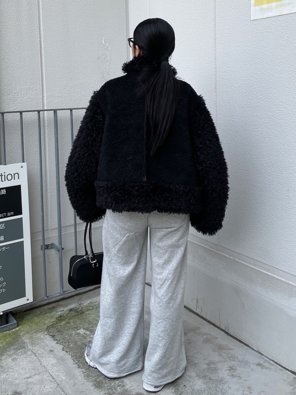 ブラック系のムートンコート、ブラック系のハンドバッグ、グレー系のスウェットパンツを着用したレディースの秋コーディネートの3枚目の写真