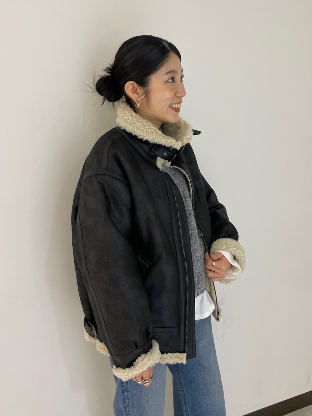 グレー系のニット/セーター、ブルー系のデニムパンツ、ブラック系のブルゾンを着用したレディースの秋コーディネートの4枚目の写真