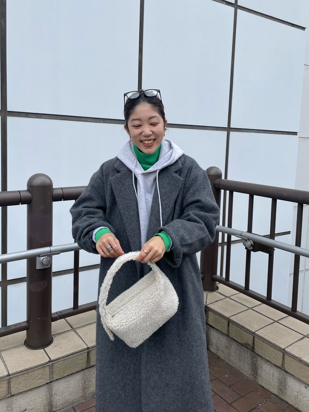 グレー系のパーカー、グリーン系のニット/セーター、ブルー系のデニムパンツを着用したレディースの秋コーディネートの6枚目の写真