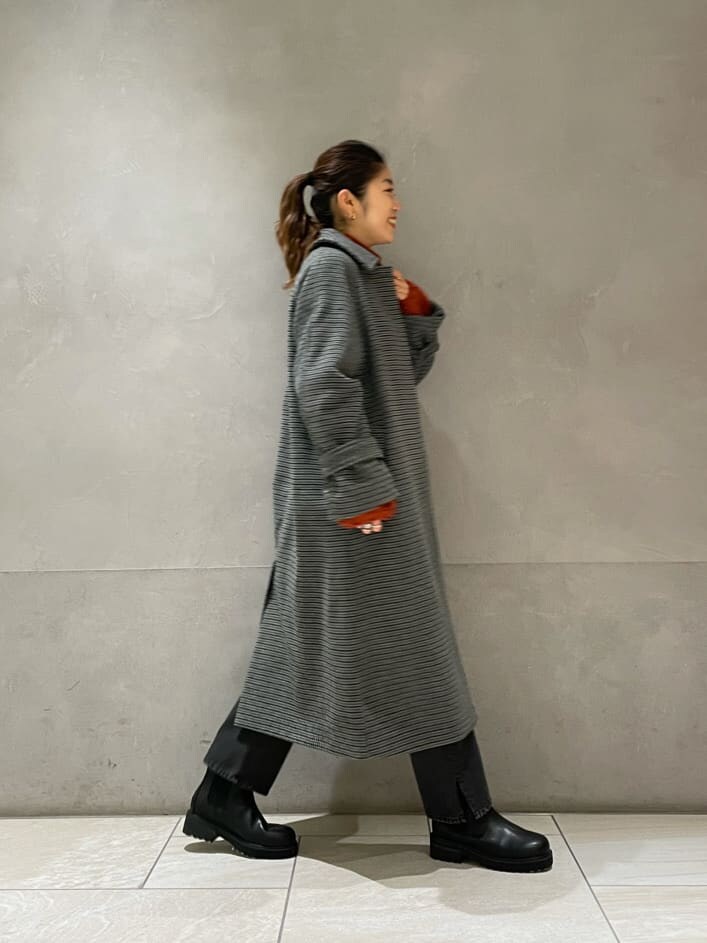 グレー系のステンカラーコート、オレンジ系のニット/セーターを着用したレディースの秋コーディネートの4枚目の写真