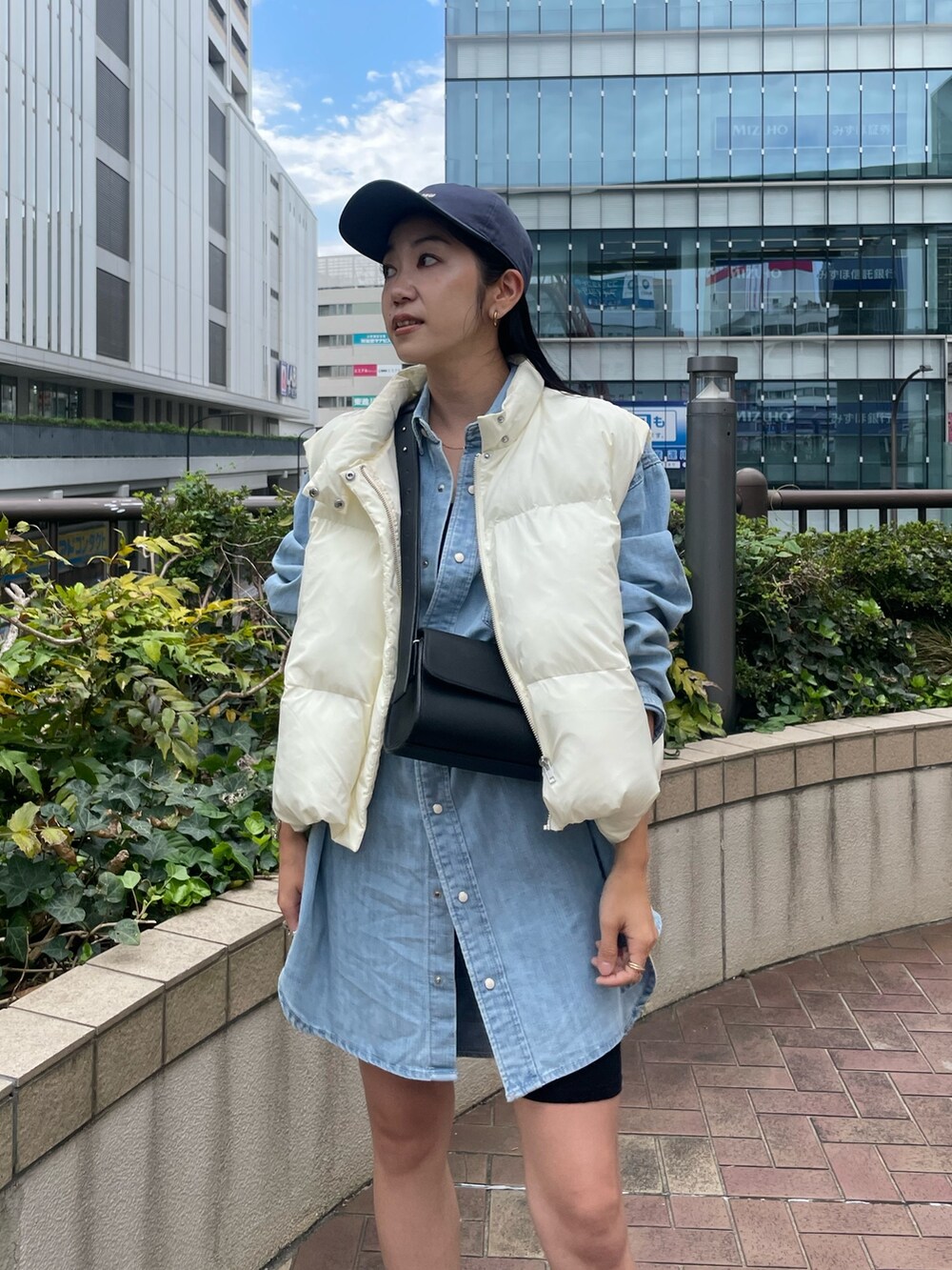 ブルー系のシャツ/ブラウス、ブラック系のショルダーバッグ、ホワイト系のダウンベストを着用したレディースの秋コーディネートの5枚目の写真