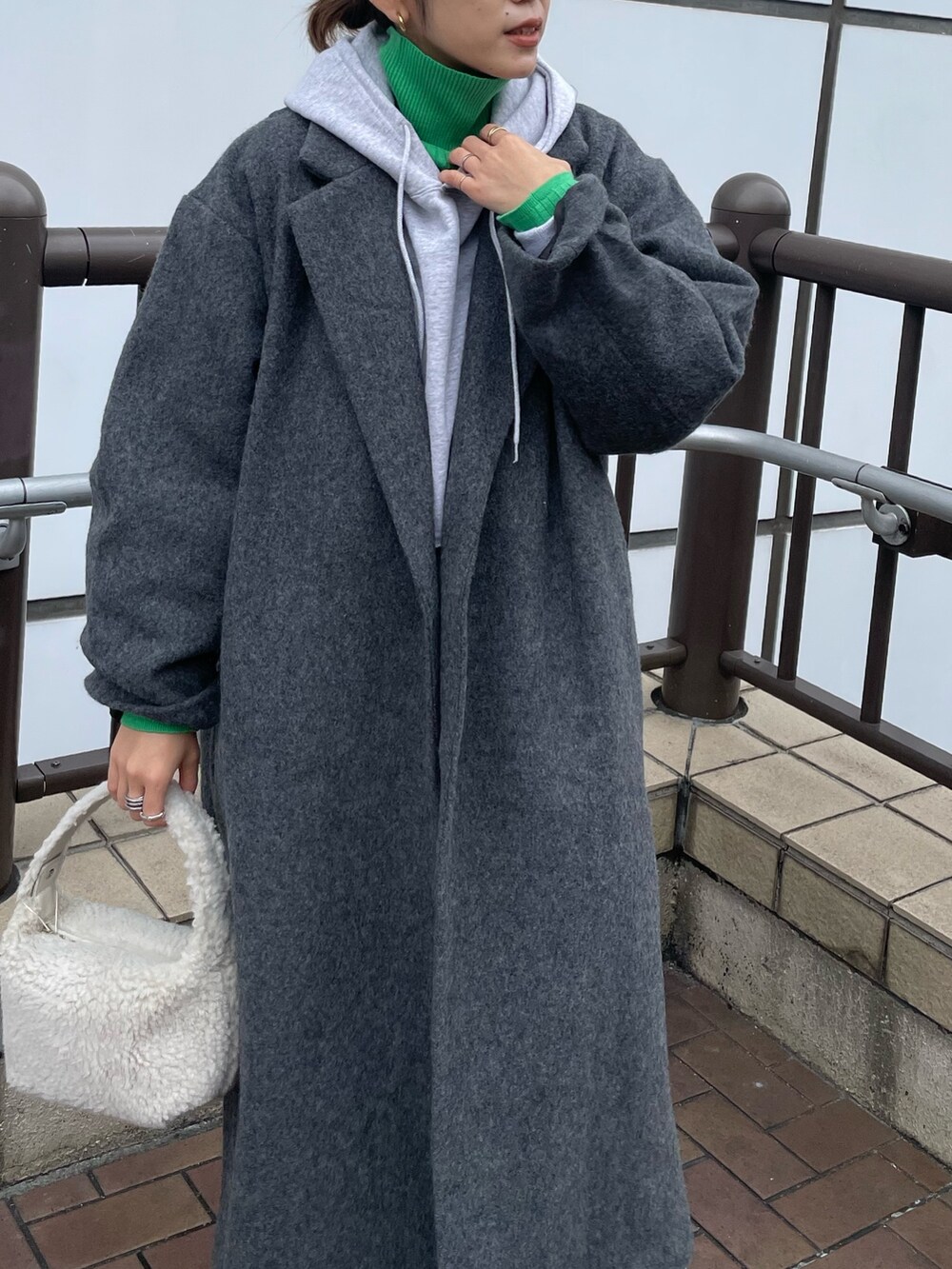 グレー系のパーカー、グリーン系のニット/セーター、ブルー系のデニムパンツを着用したレディースの秋コーディネートの2枚目の写真