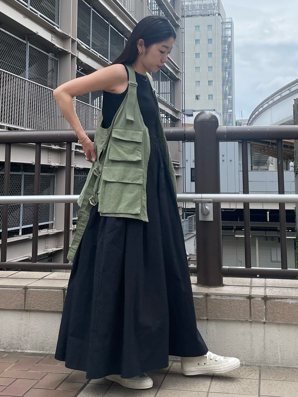 ブラック系のワンピース、ベージュ系のベスト、ホワイト系のスニーカーを着用したレディースの春コーディネートの3枚目の写真